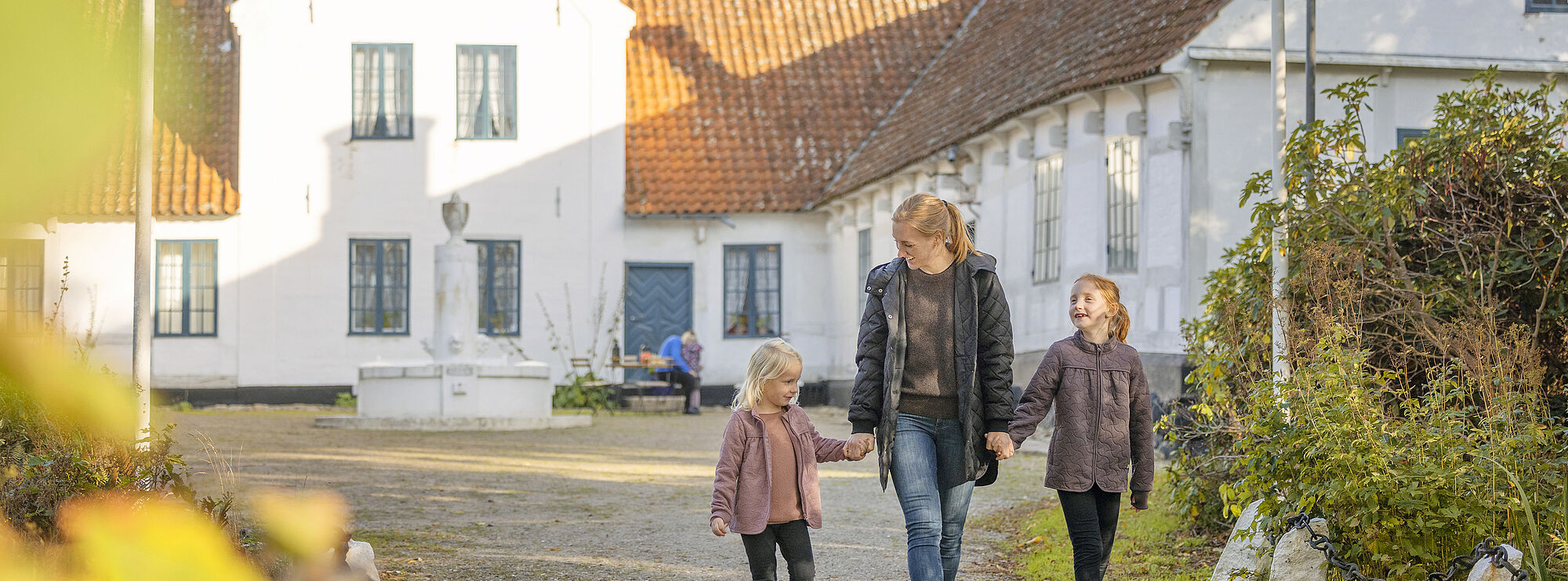 Billede af en mor, der går med sine to piger, foran Bangbo Museum